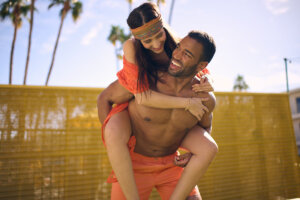 Couple with smooth skin smiling and laughing in an outdoor setting, showing the benefits of waxing shoulders and back.